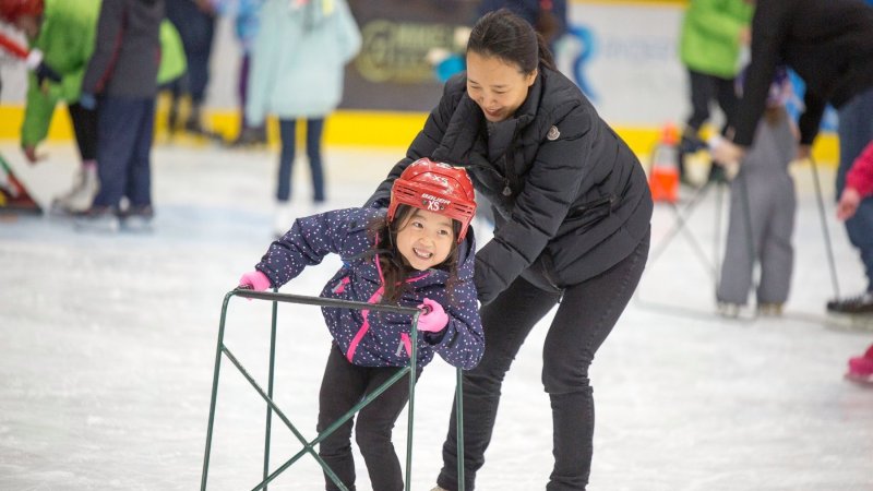 A mom and daughter ice skating.