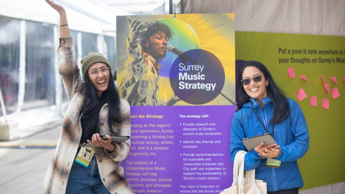 Two women smiling and standing at Surrey Music Strategy engagement booth