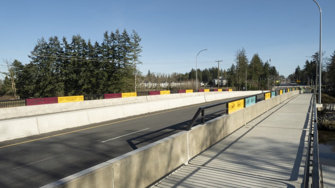 A side path with colorful barrier panels under a blue sky.