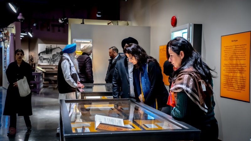  Visitors attentively viewing an exhibition display in a museum gallery.