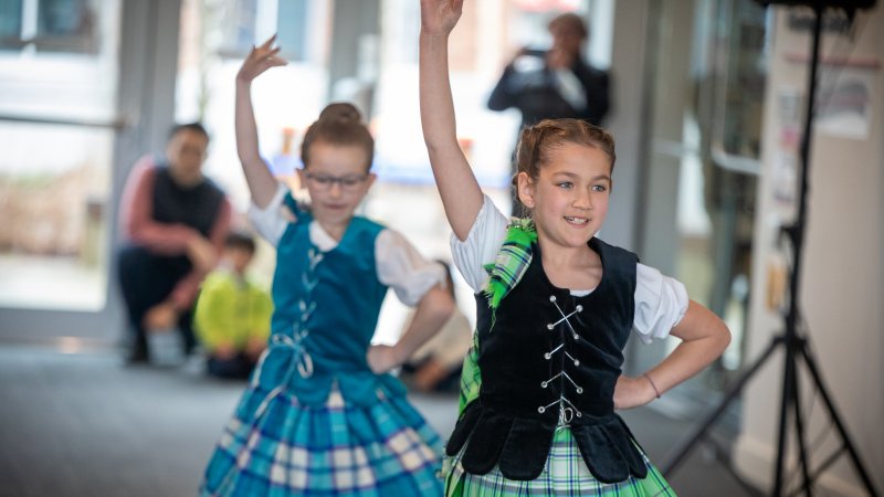 Two young girls in traditional Celtic dance attire perform.