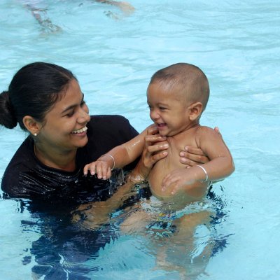 A mother swimming with their child.
