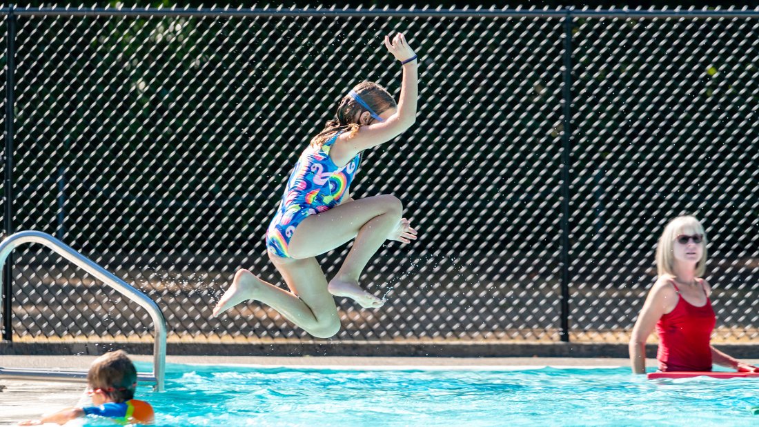 Girl jumping into outdoor pool