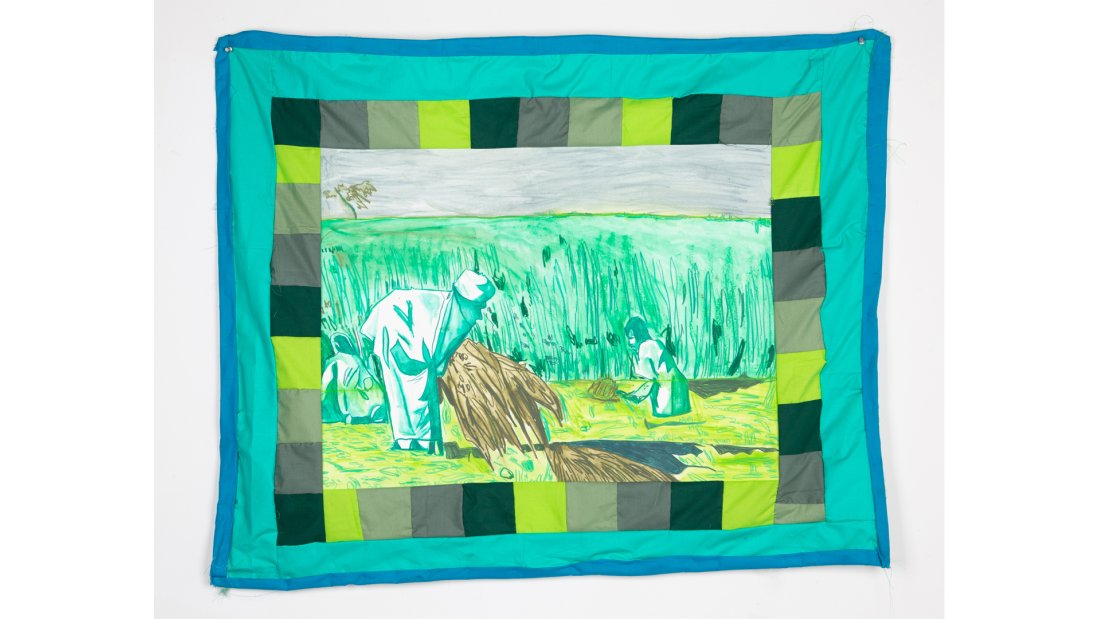 Quilt with various green squares bordering a scene of farmworkers pulling up hay against a tall grassy field.