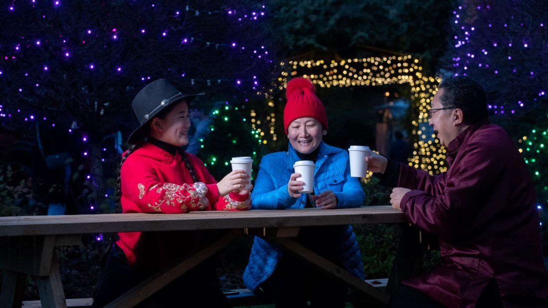 family enjoys hot chocolate at a picnic table