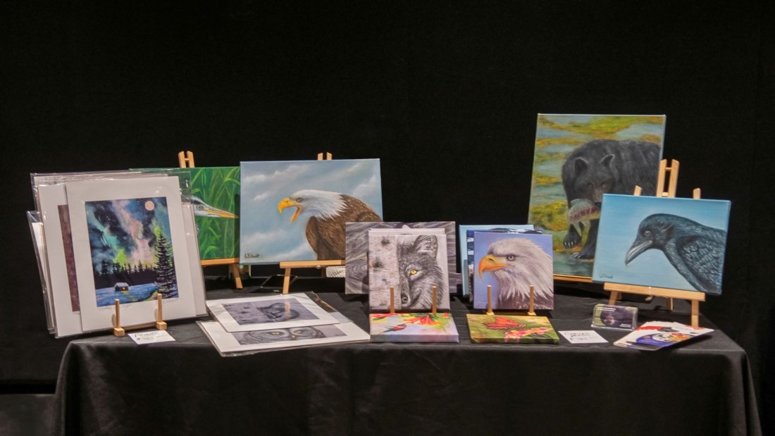 A variety of wildlife paintings, prints, and cards displayed on a table.