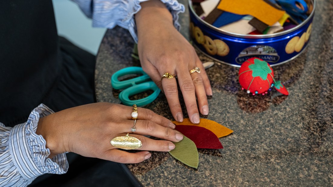 A woman's hands are placing felt shapes on a table.