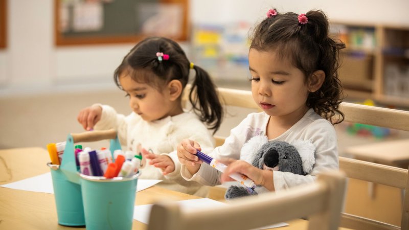 Two kids colouring at a desk.