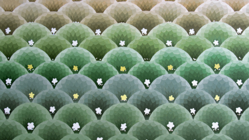 Repeated patterns and point by point brush strokes. These patterns are gradients of green that play with light and shadow. There are rows of round domes that give a prismatic look. Each dome partially covers the bottom of the dome above it. From a glance, it can appear to tbe the tops of the trees. On each dome is a yellow or white flower shape. 