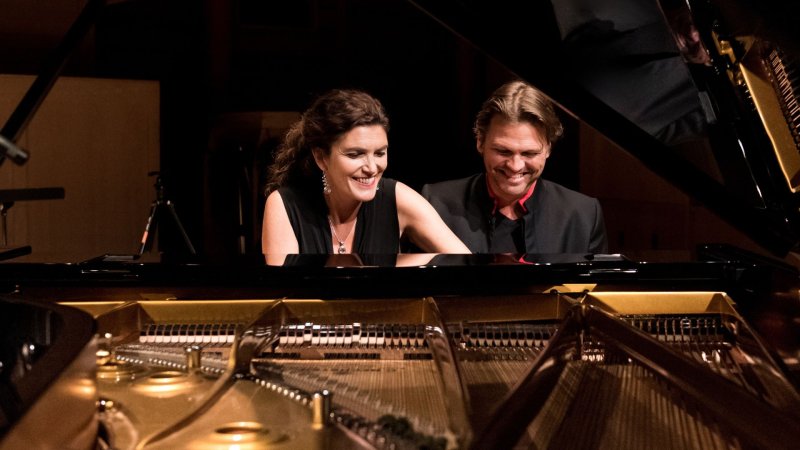 The Bergmann Duo play the grand piano together and are smiling
