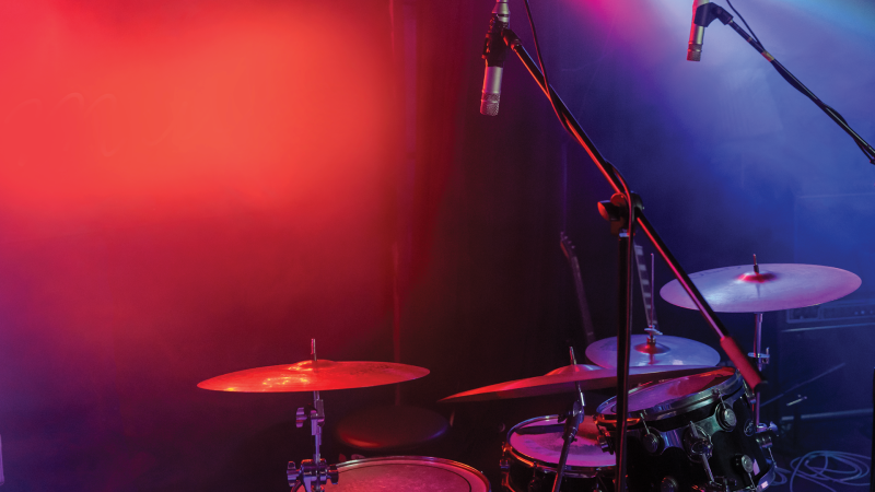 A drum kit bathed in red and purple light