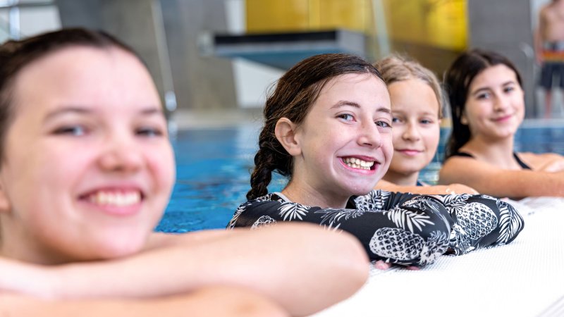 Girls in the pool smiling.