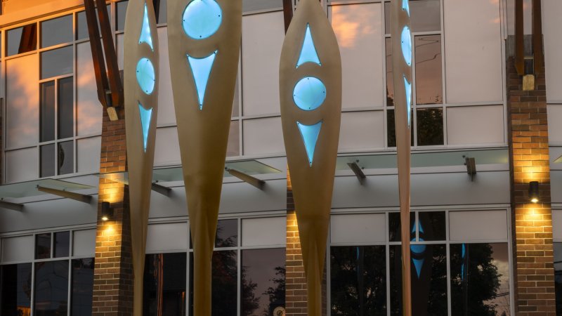 Four wooden paddles lit up in orange point to the sky from the ground