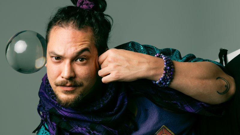 Chris Murdoch wears a bun in his hair and raises one eyebrow as he appears to be falling. A bubble touches the right side of his face.