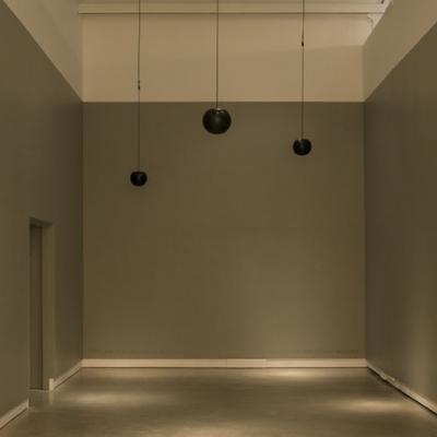 An empty room with 3 mini speakers handing from the ceiling