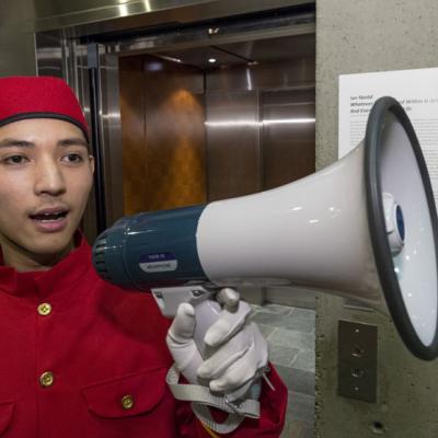 A man in a red bell boy costume with a white megaphone