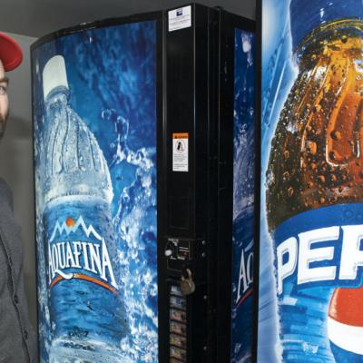 A man in a ball cap stands next to vending machines