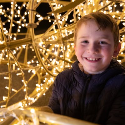 boy smiles next to white lights