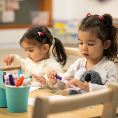 Two kids colouring at a desk.