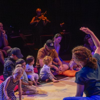 performance space children and adults sitting on the floor as a performer dances