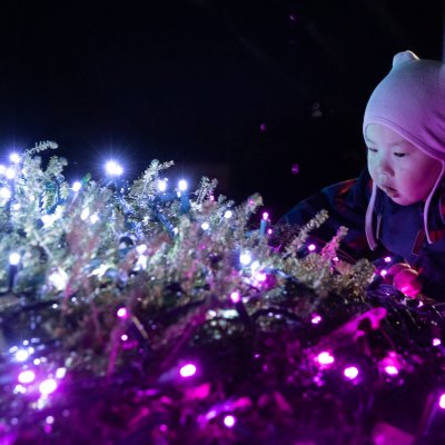 a young child crouched down admiring a light display