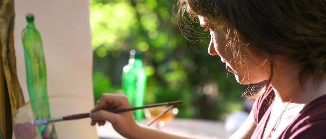 Young girl paints a picture outdoors