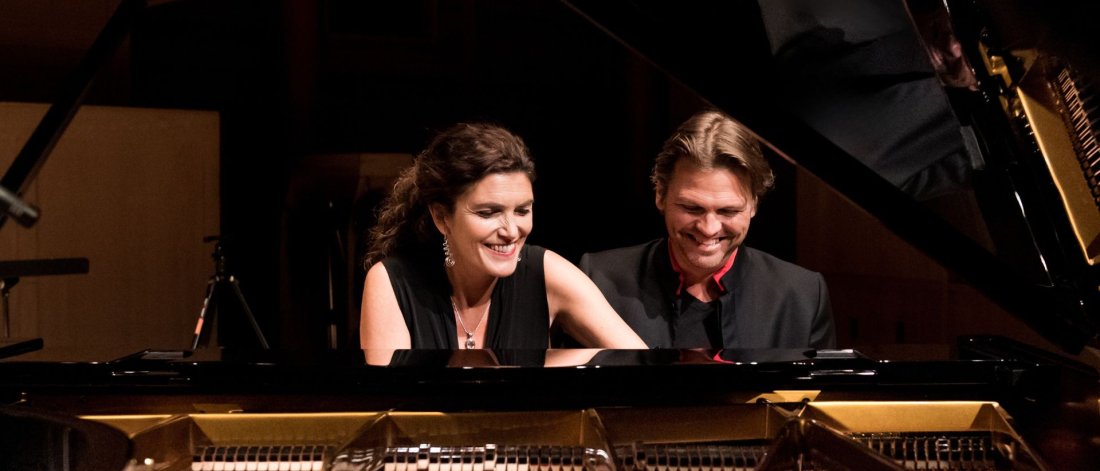 The Bergmann Duo smile as they play the grand piano together