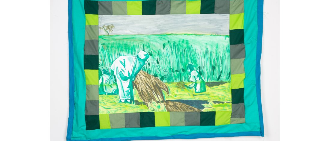 Quilt with various green squares bordering a scene of farmworkers pulling up hay against a tall grassy field.