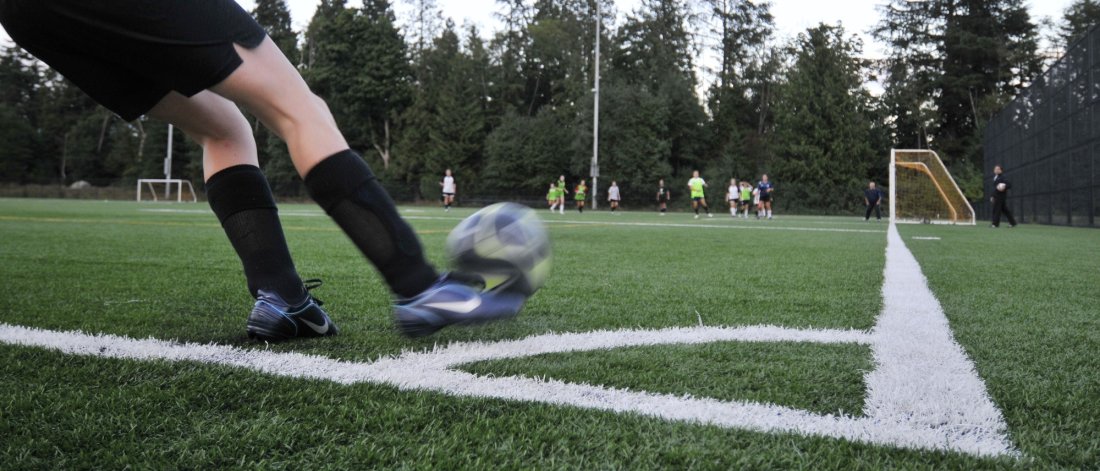 person kicking soccer ball on outdoor field