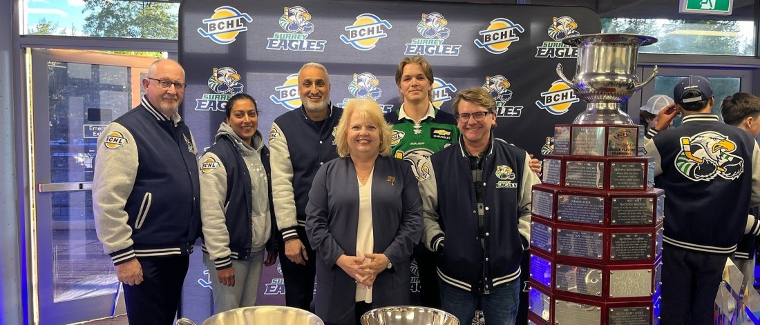 Mayor Brenda Locke and Surrey Eagles staff posing in a group photo with the Fred Page Cup trophies on display at the Surrey Eagles clubhouse.