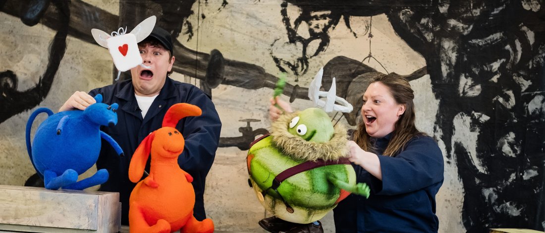 Two actors on set with three puppets from the performance 