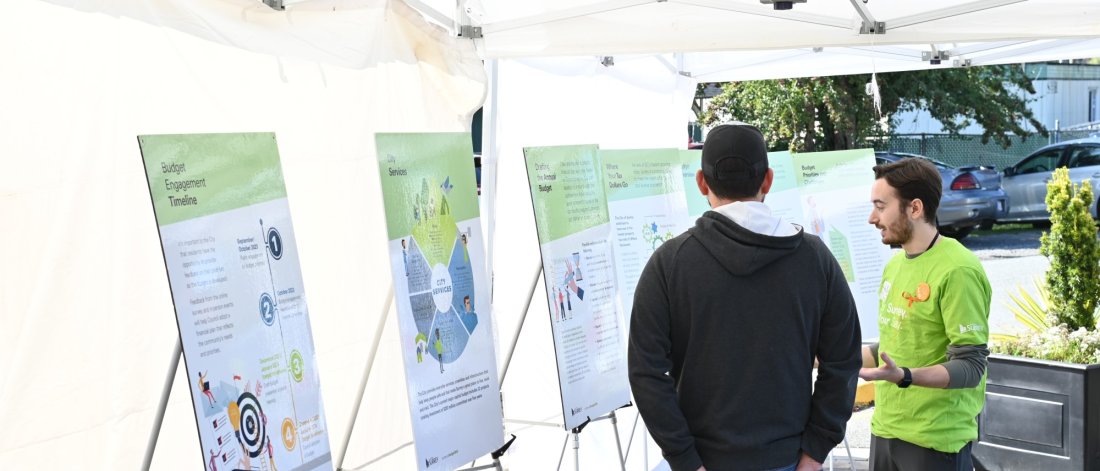 Community engagement booth with information panels on city services and budget processes in Surrey