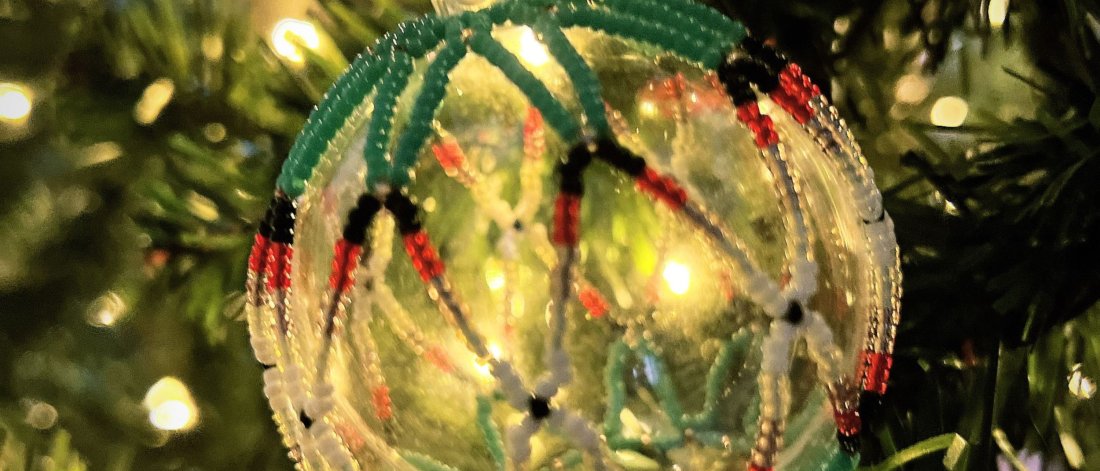 A beaded Christmas ornament hung in a tree