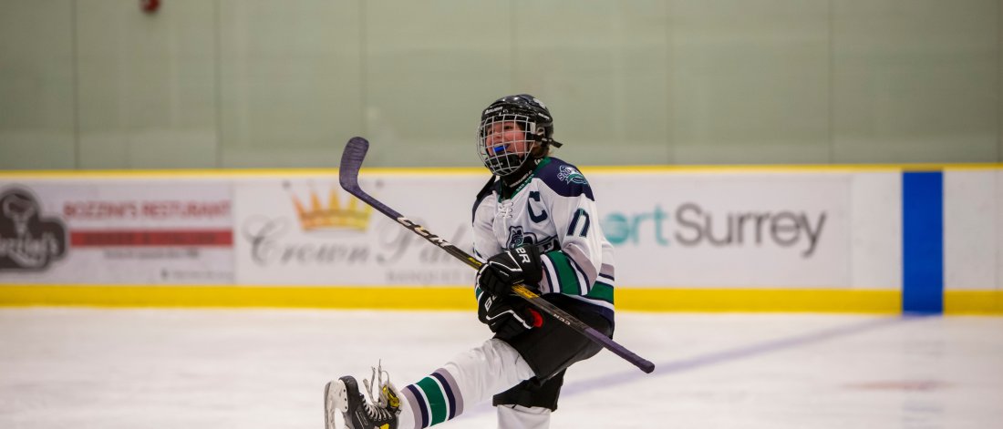 Female hockey player celebrating a goal on one leg. 