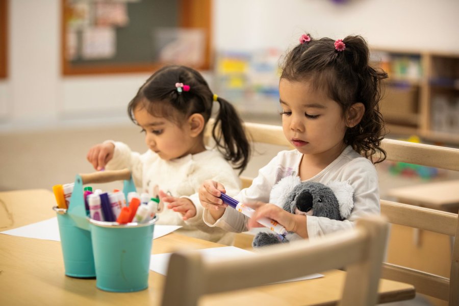 Two kids colouring at a desk.