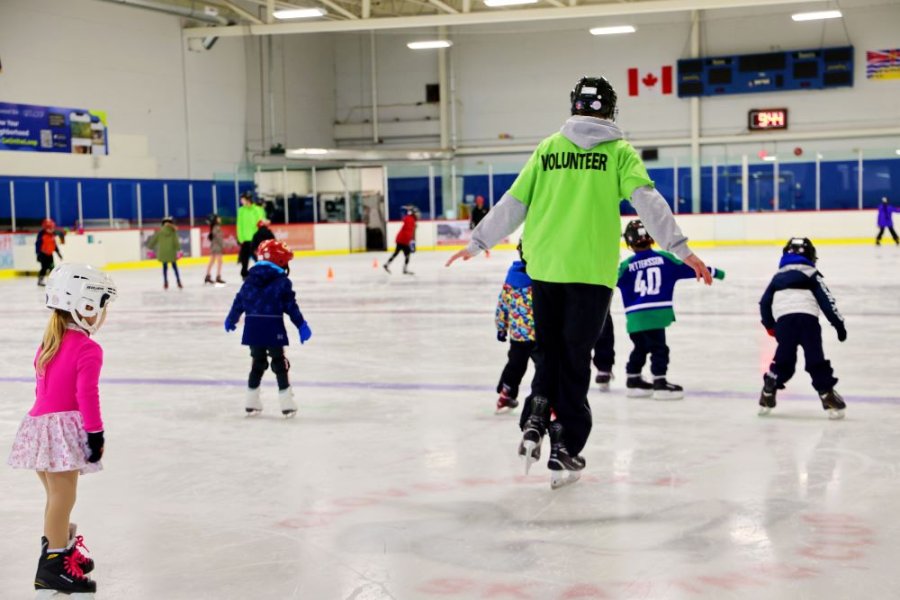 A skating instructor and a group of children participants.