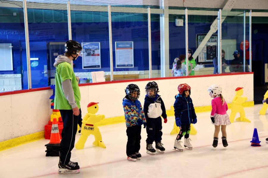 A skating instructor and a line up of kids.