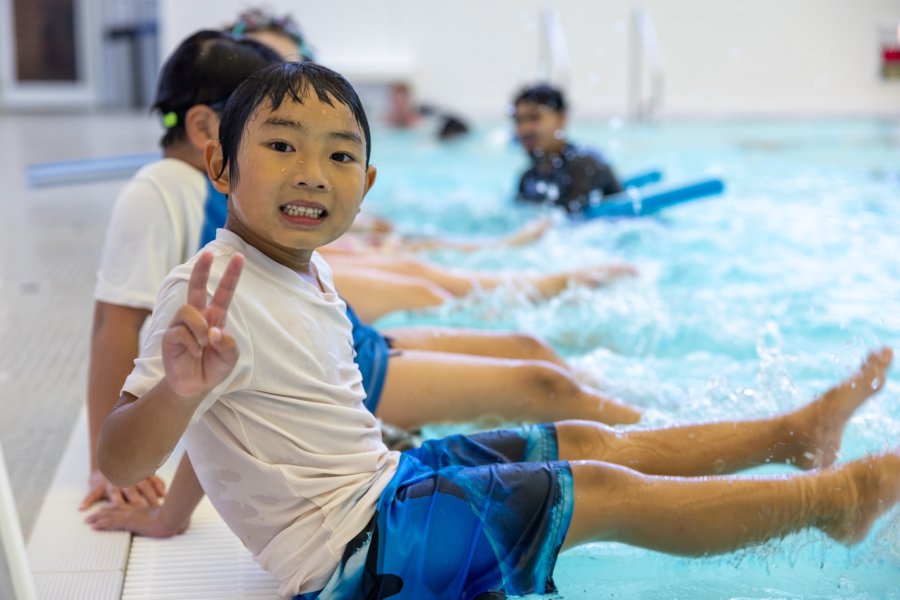 a boy is sitting at the side of an indoor pool