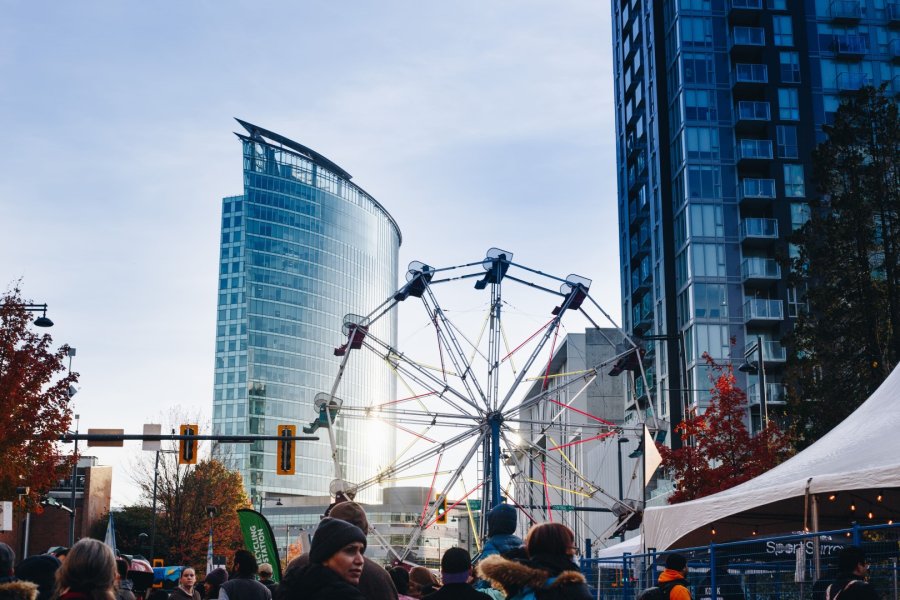  A Ferris wheel set against the backdrop of modern city buildings, with a crowd of people looking around.