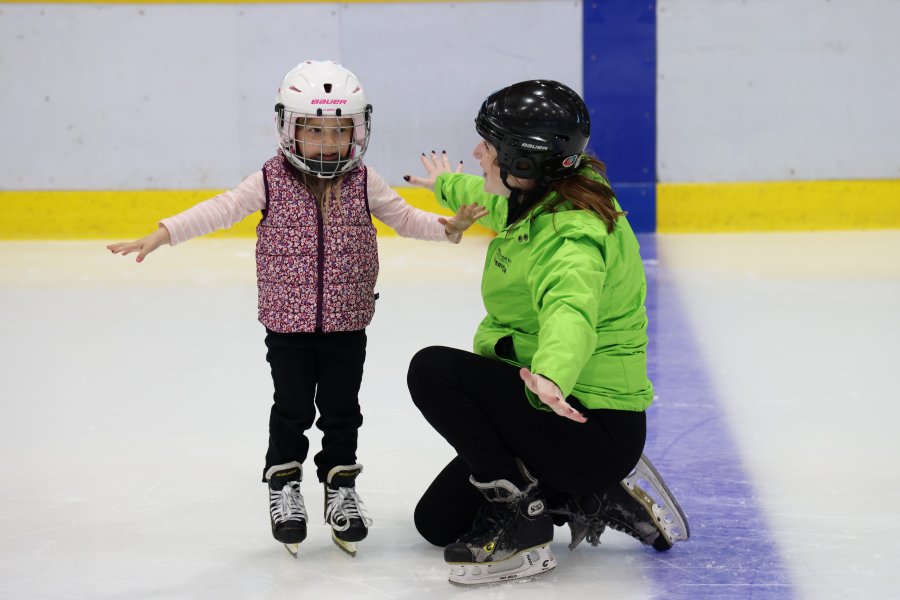 An instructor showing a child how to ice skate.