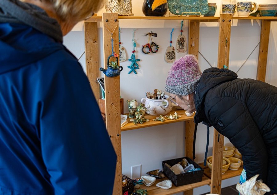 A person looking at art on a shelf.